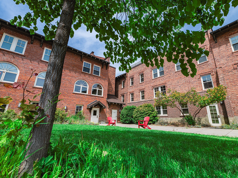 Brick residence hall with red lawn chairs in front