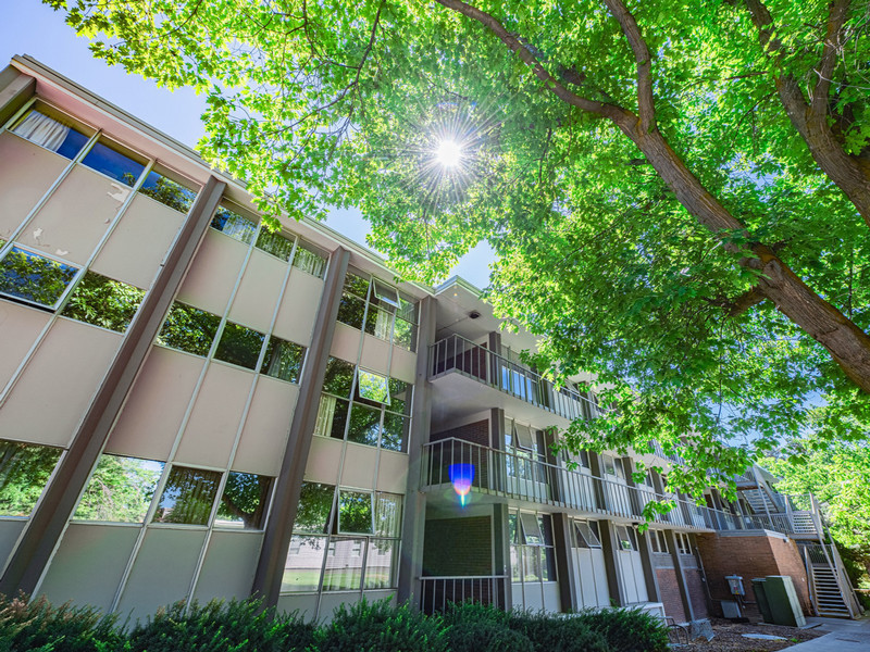 Three-story residence hall with lawn and trees around it