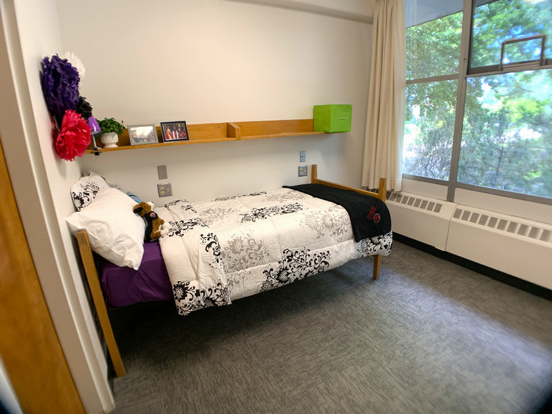 Twin XL bed with shelf above it and window to one side
