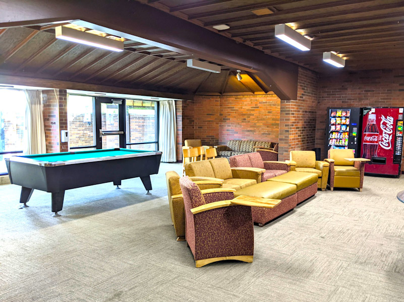 Student lounge with couches, chairs, tables, TV, and pool table