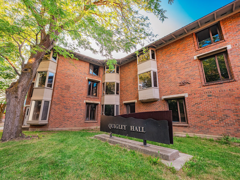 Three-story brick residence hall with a covered porch over the entrance