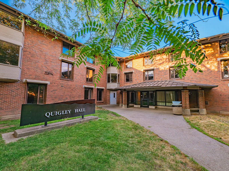 Three-story brick residence hall with a covered porch over the entrance