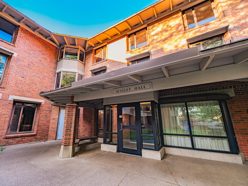 Three-story brick residence hall with a covered porch over the entrance