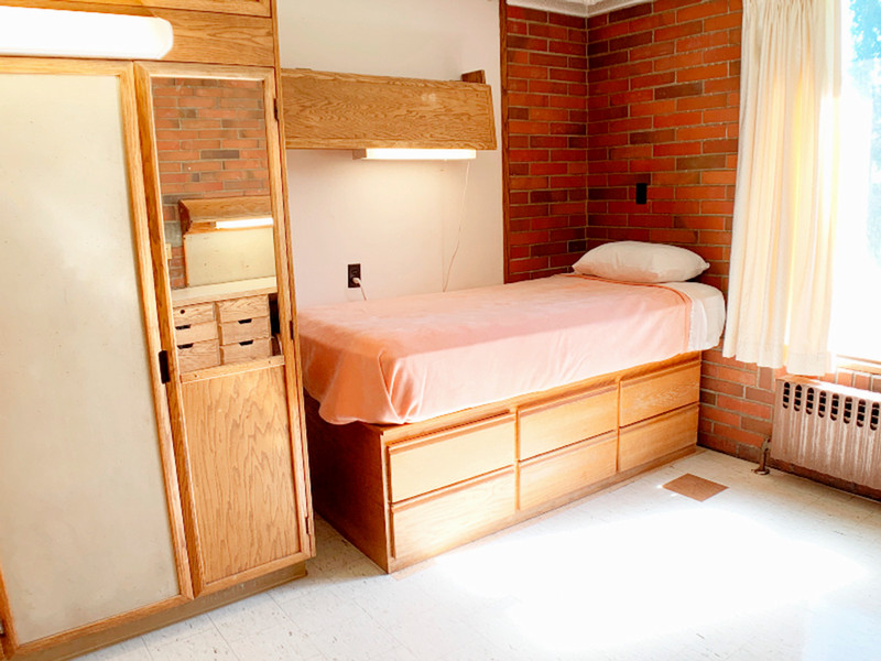 Twin XL bed with shelf above it and window next to it