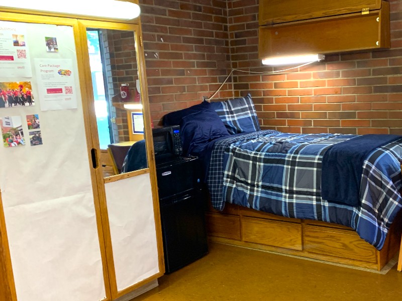Twin XL bed with shelf above it and microfridge unit next to it