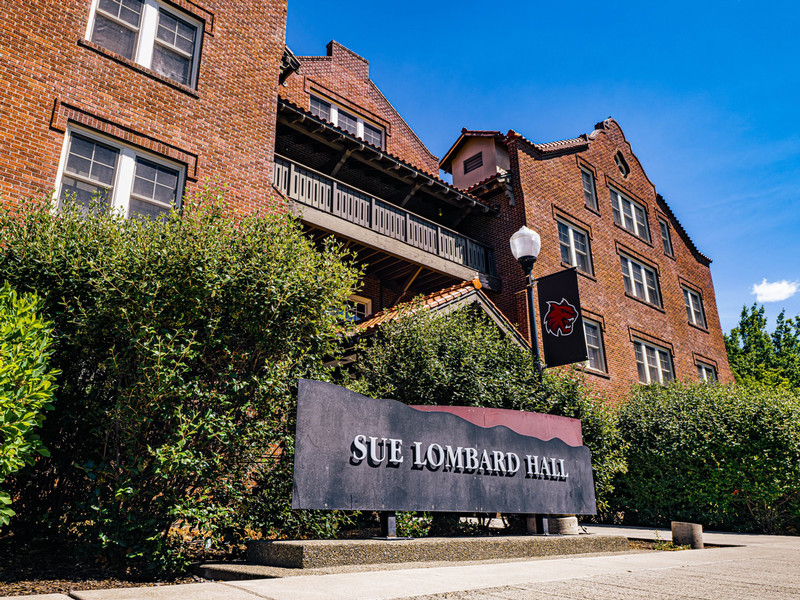 Historic 4-story brick residence hall with balcony and terracotta roof