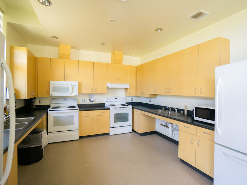 Kitchen with two fridges, two ovens, sinks, and a microwave