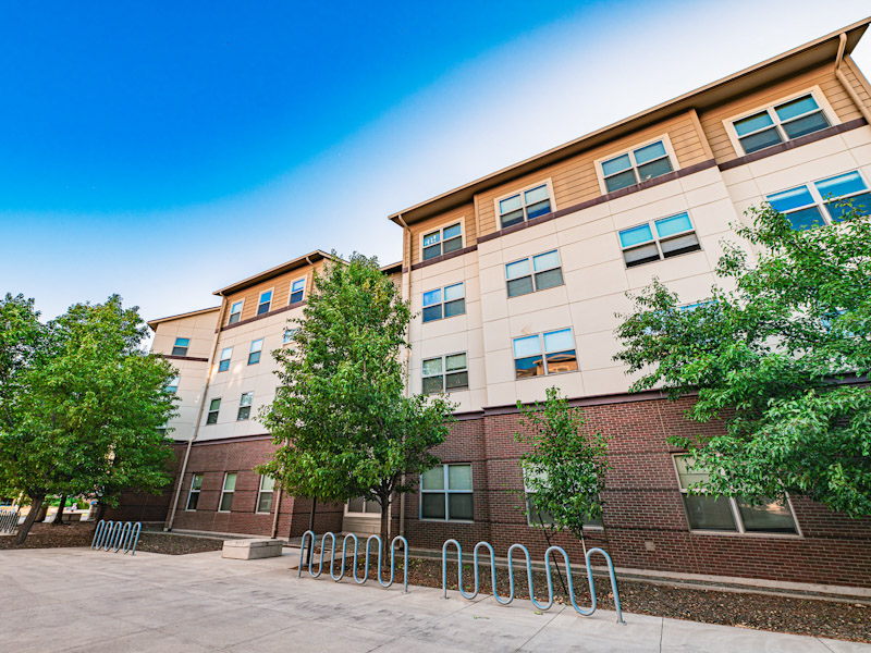 Outside of a four-story modern residence hall with a bicycle rack