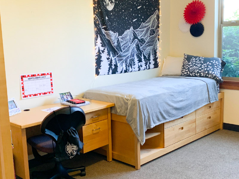 Twin XL bed with a window on one side and a desk on the other side