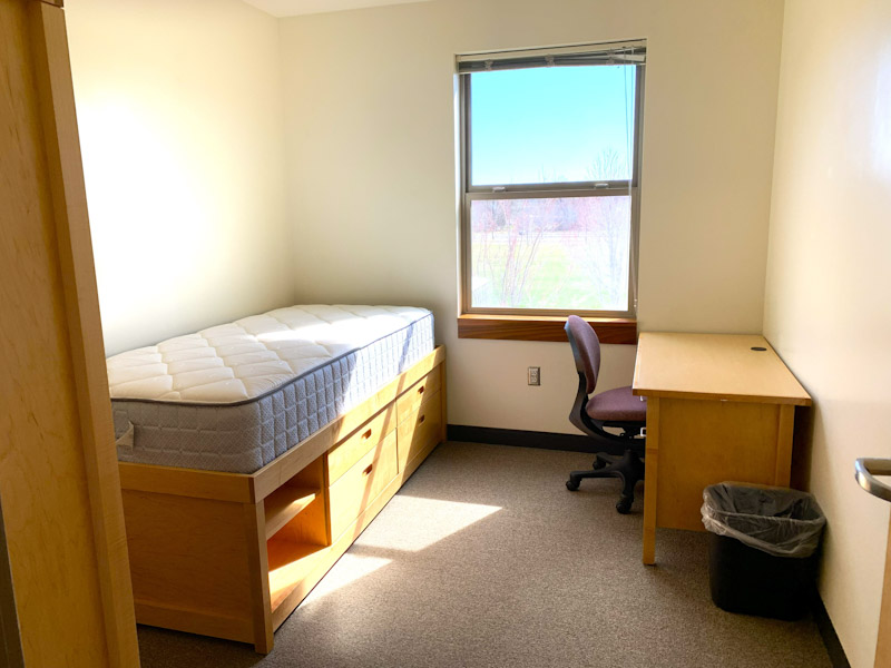 Single room with bed, desk, desk chair, and a window