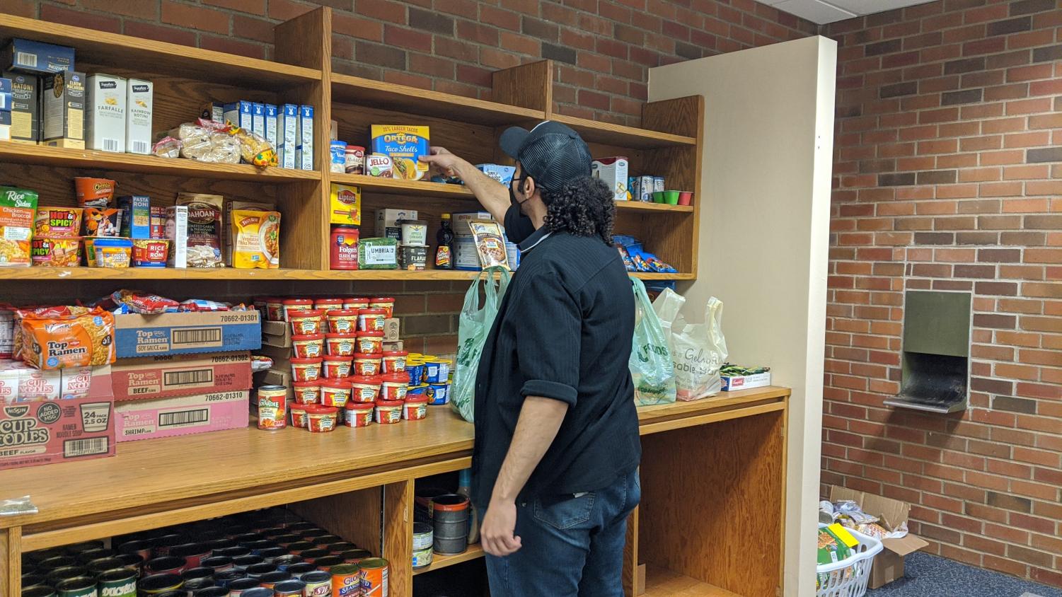 Student reaching out to grab food from the pantry shelf.